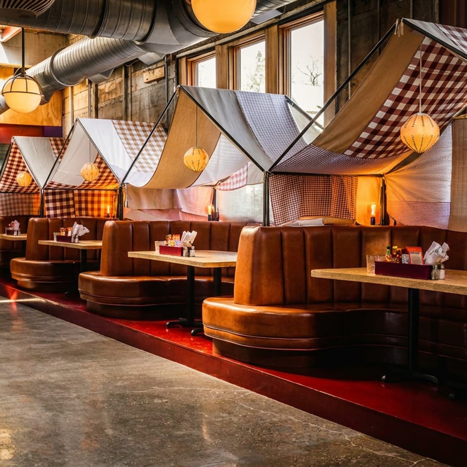 Cozy restaurant interior with leather booths, checkered canopy-like decor, exposed ductwork, and warm pendant lighting.